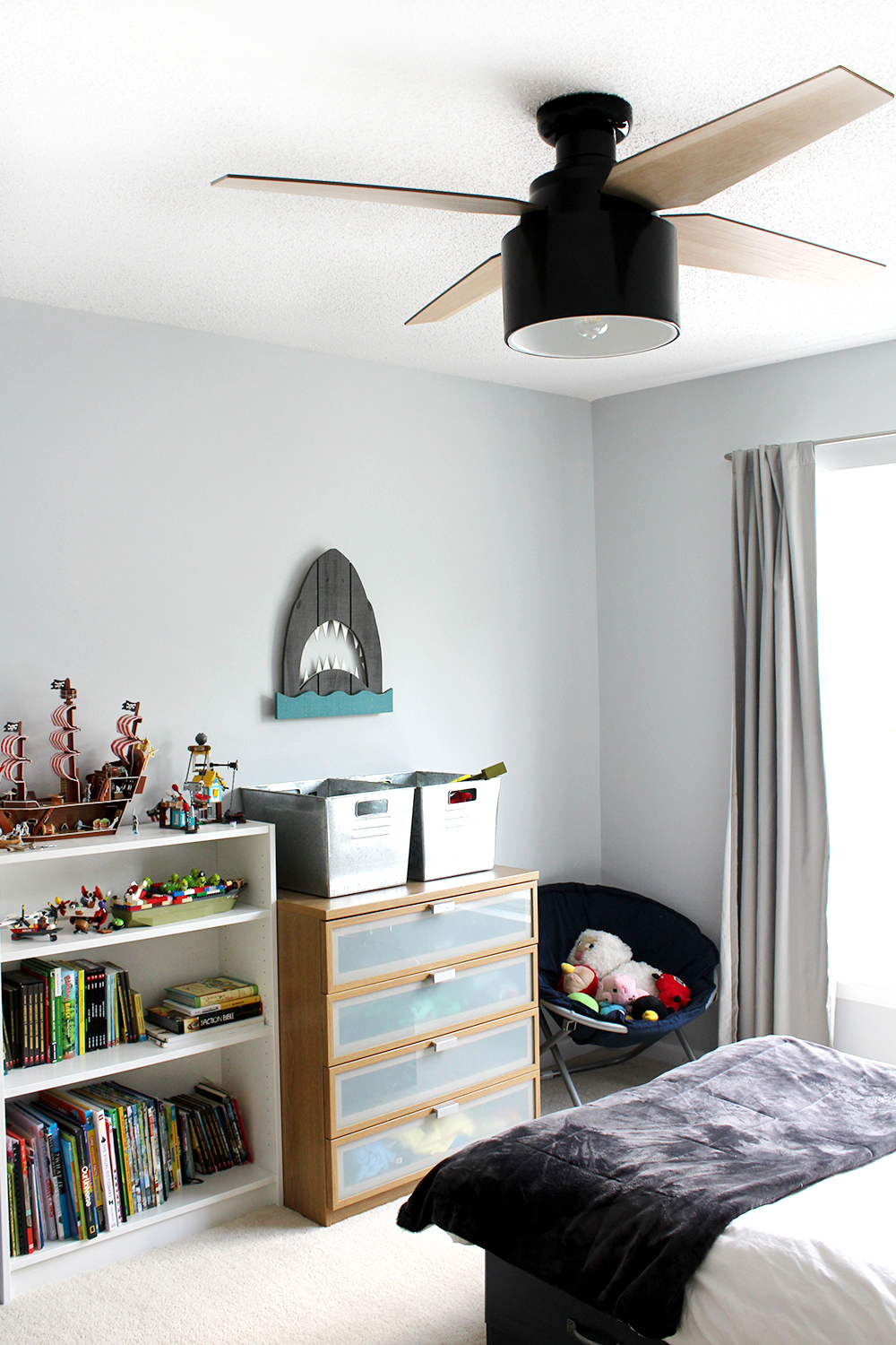 preteen boy's room with blue-grey walls and modern black ceiling fan